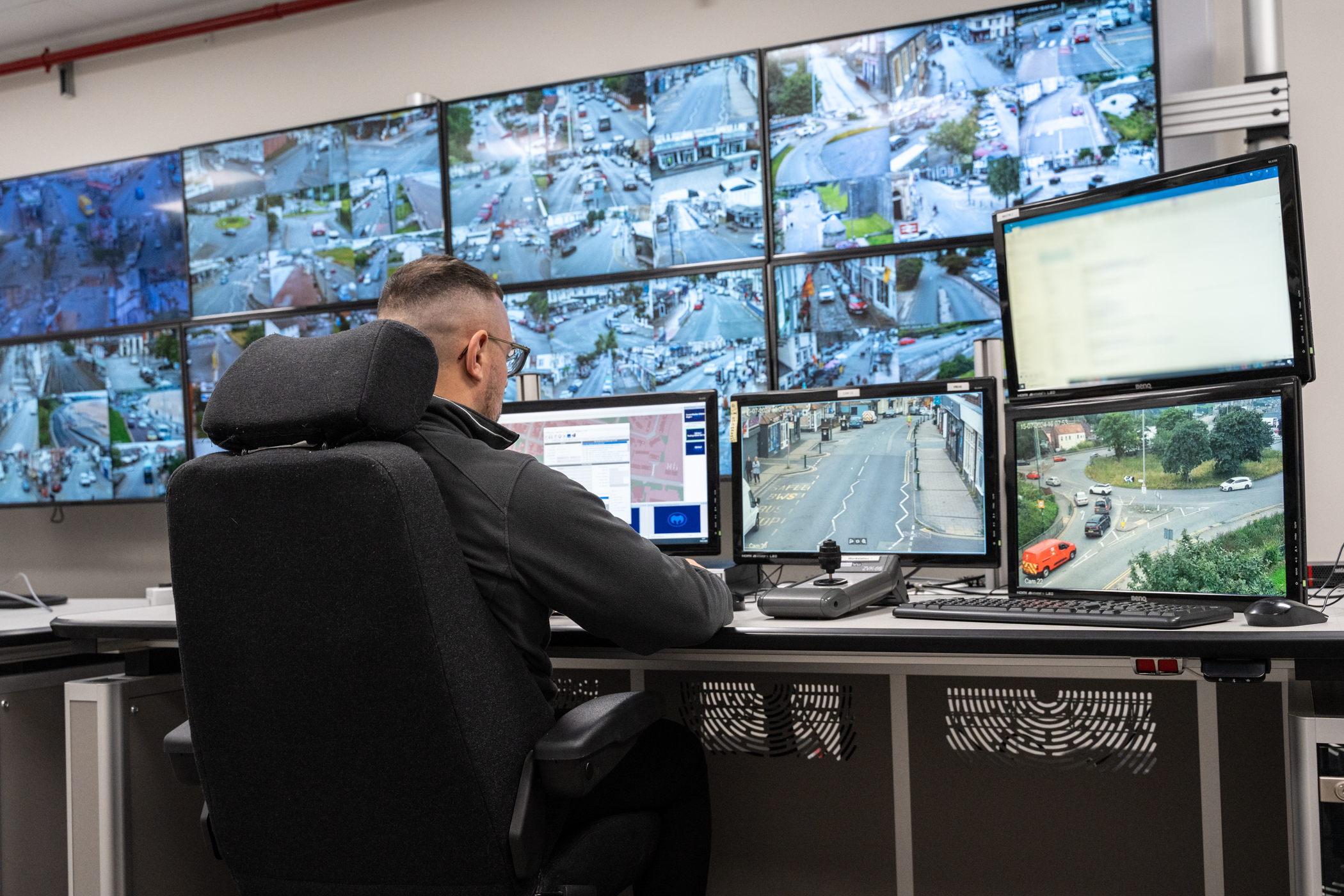 CCTV operator sat at a bank of monitors.